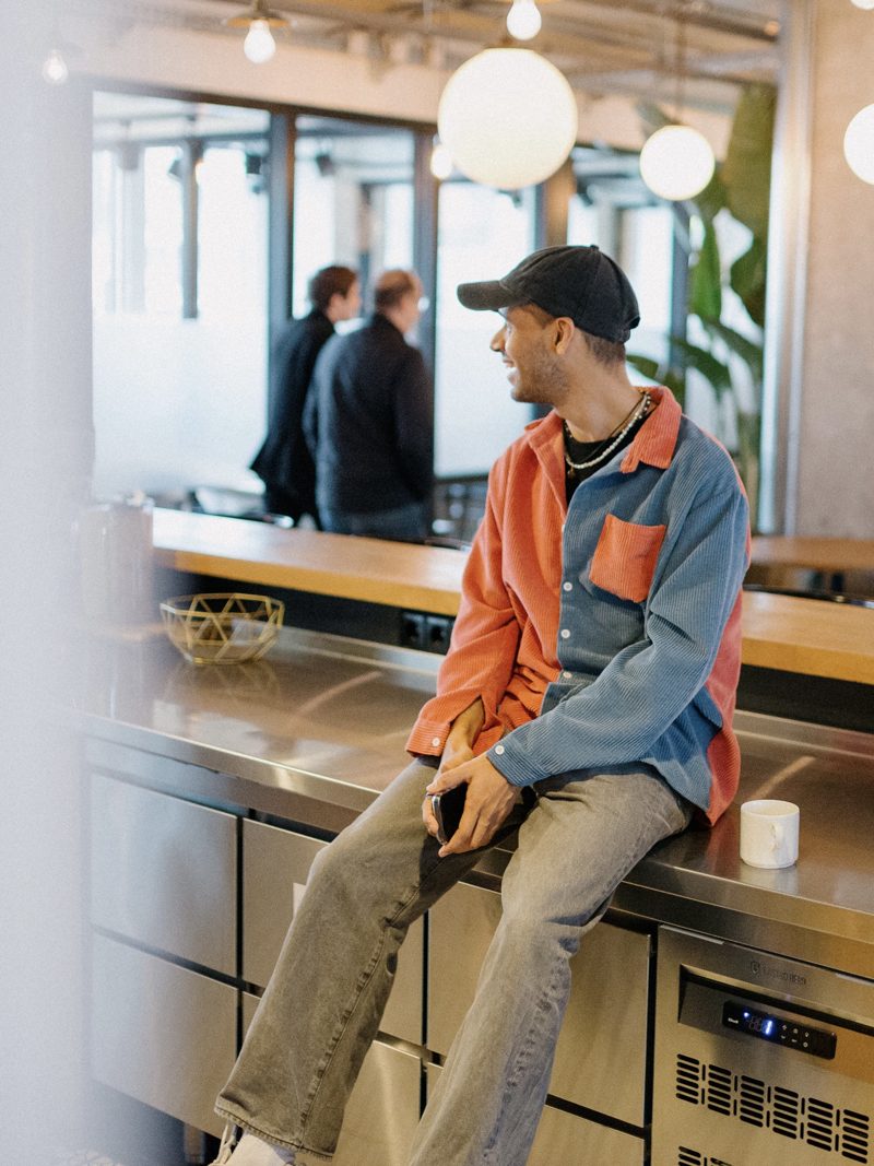 Manoj sitting on a kitchen counter in a co-working space, looking out of frame
